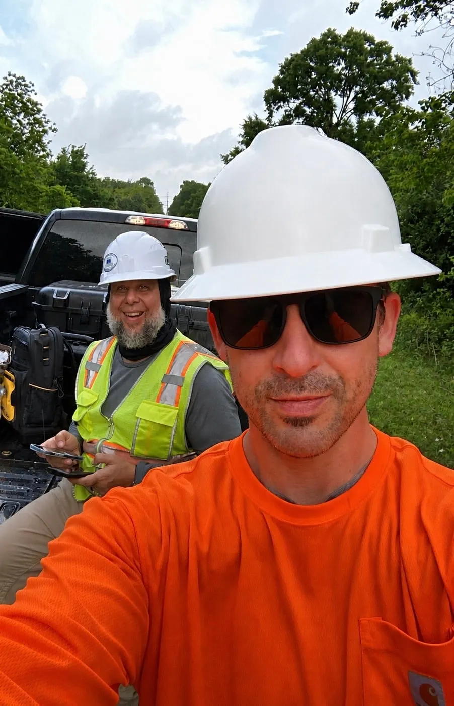 Two Axis crew members in hard hats and high-visibility vests at the truck between flights, one holding the controller.