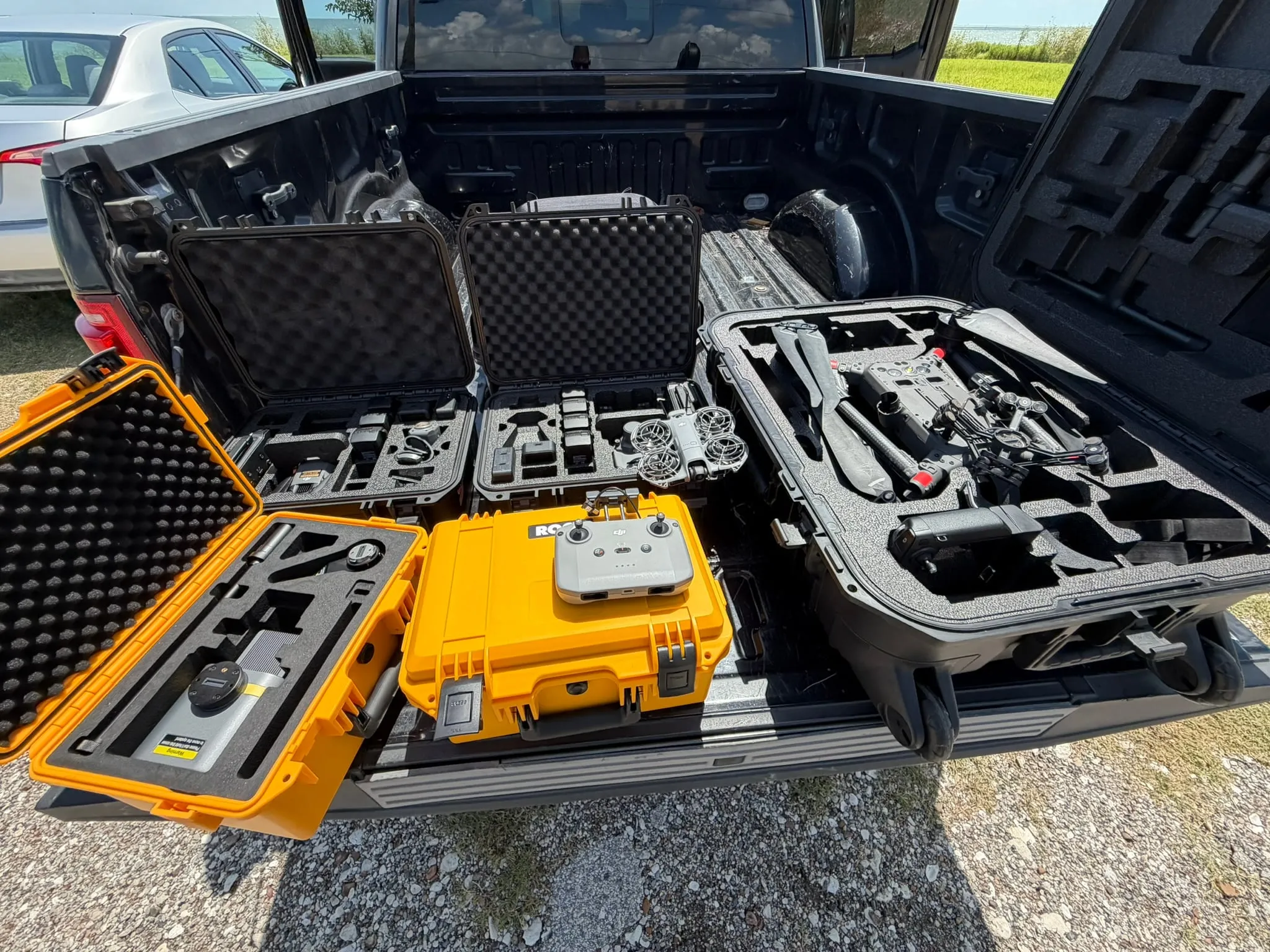 Field cases open in the bed of the truck: aircraft, LiDAR payload, batteries and controllers staged for mobilization.