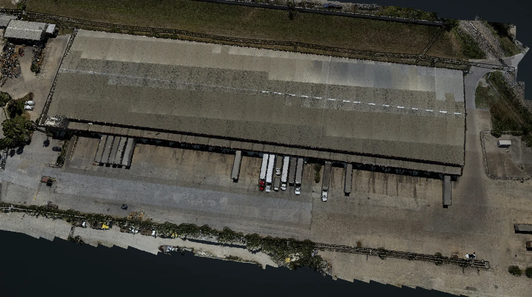 RGB-colorized LiDAR point cloud of the Loera Brokerage warehouse, viewed from above: loading docks with trailers along the south face and the surrounding yard.